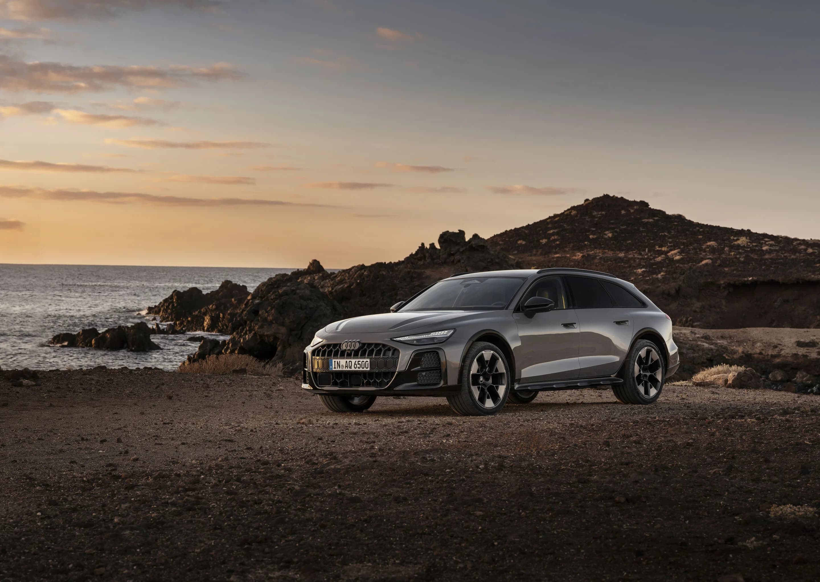 Audi A6 allroad quattro - Audi A6 allroad (plateau grey metallic) in side view at a rugged coastal landscape during sunset.
