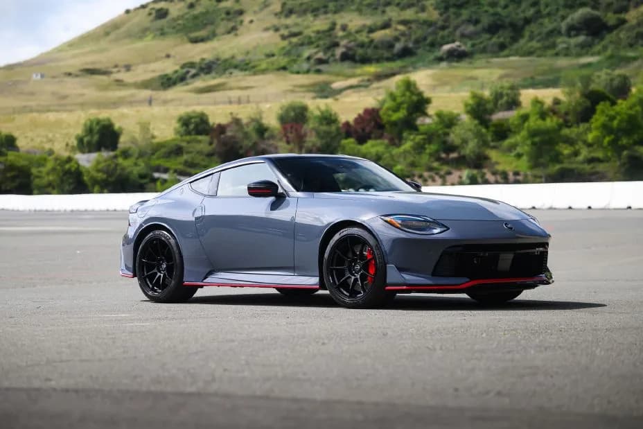 Front right 3/4 view of the 2027 Nissan Z NISMO Manual Transmission parked on asphalt with trees behind.