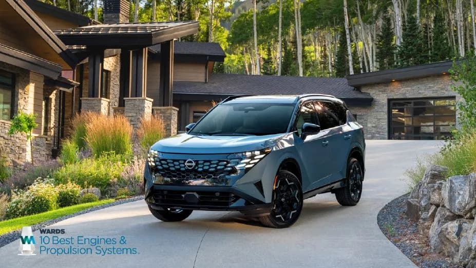Front left ¾ view of the 2027 Nissan Rogue hybrid parked in front of a house, a Wards 10 best logo is in the bottom left.