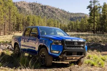 Front right 3/4 view of the 2027 Nissan Frontier Sport Edition parked in a wooded area.