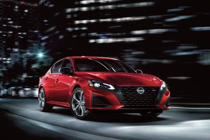 Front right 3/4 view of the 2027 Nissan Altima parked on city streets at night.