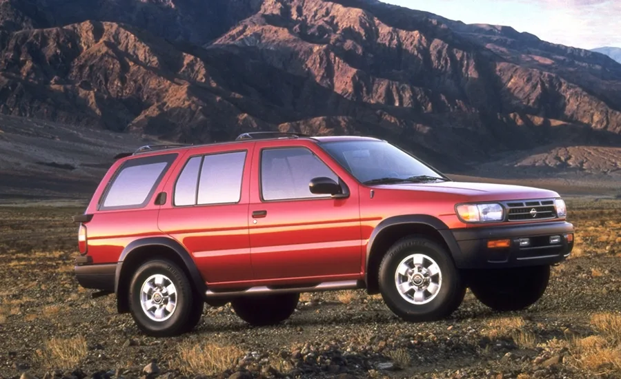 Front right 3/4 view of the early-generation Nissan Pathfinder parked near a mountain range.