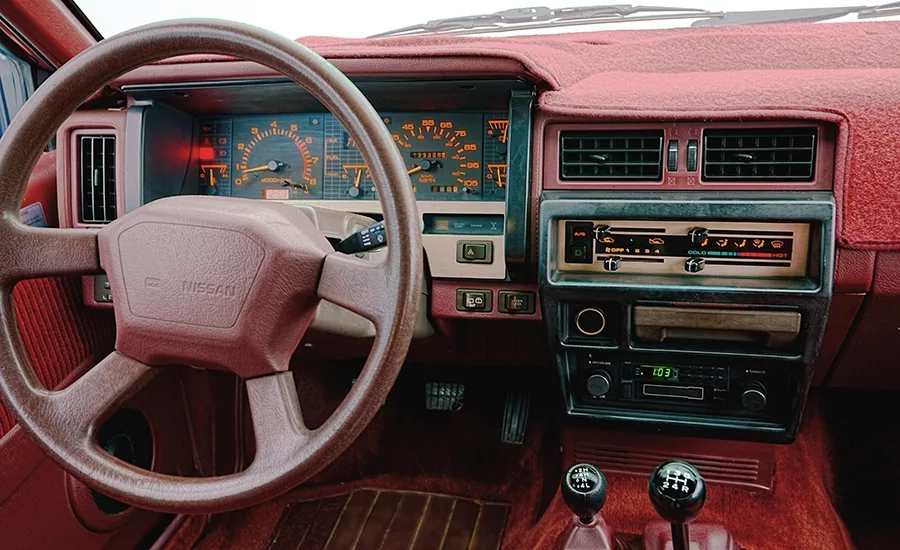 The burgundy steering wheel and interior inside the 1987 Nissan Pathfinder.